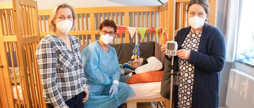 Arvid liegt ruhig in seinem Pflegebett und atmet regelmäßig. Intensivpflegerin Beate Götz setzt sich zu dem Jungen auf die Bettkante und nimmt seine Hand. Dann spricht sie mit ihm und massiert seine Schultern.