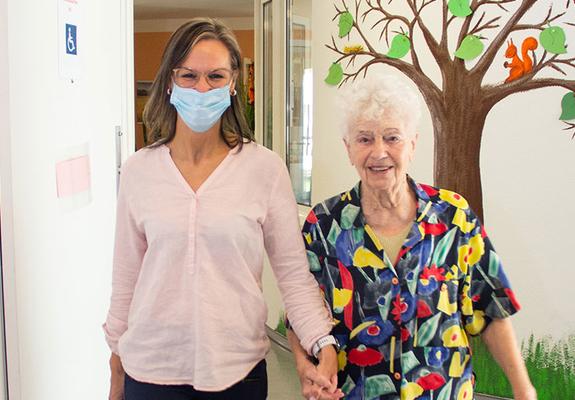 Pflegedienstleiterin Antje Nowack begleitet einenTagesgast zur Bingorunde mit den anderen Gästen der Einrichtung in der Justus-von-Liebig-Straße