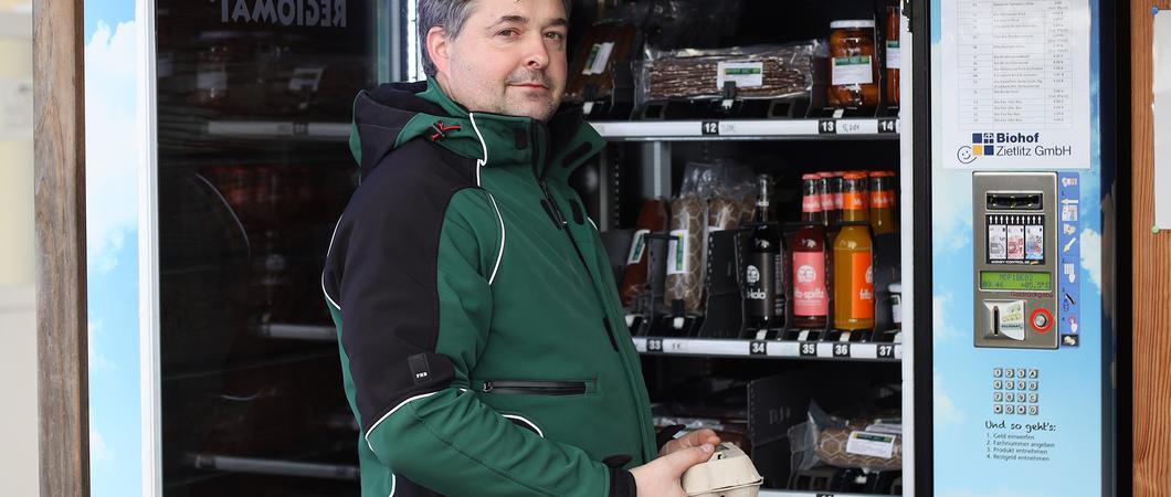 „Hier frische Eier“ steht auf dem Schild am Zaun des Bauernhauses – daneben ein kleiner Unterstand, darin die Eier- packungen und die Schachtel für das Geld.