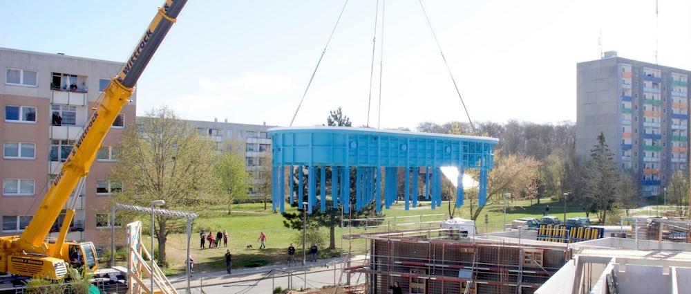 Technische Maßarbeit. Mit einem Spezialkran wird das nierenförmige Schwimmbecken vom Schwerlasttransporter in den vorgefertigten Betonausschnitt gehoben