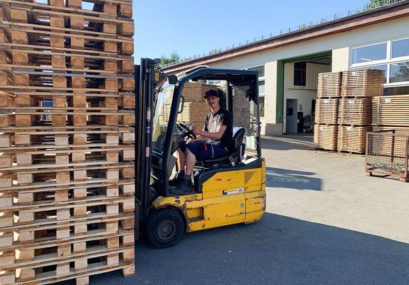 Marcel Stahnke stapelt gefertigte Paletten im Holzlager