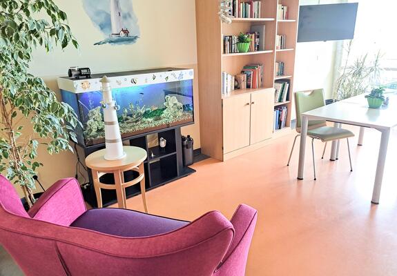 Die Bibliothek der Kurzzeitpflege „Friedensberg“  ist nebst Bücherregal, mit einer roten Couch und einem großen Aquarium gemütlich ausgestattet, Foto: Netzwerk für Menschen