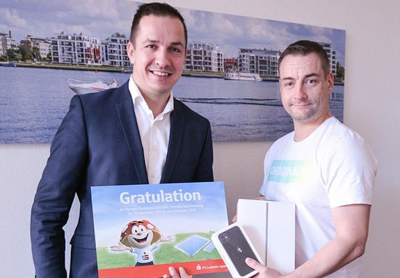V.l.: Michael Jastram (Sparkasse) überraschte Felix Zech mit dem Gewinn eines Mobile-Paketes