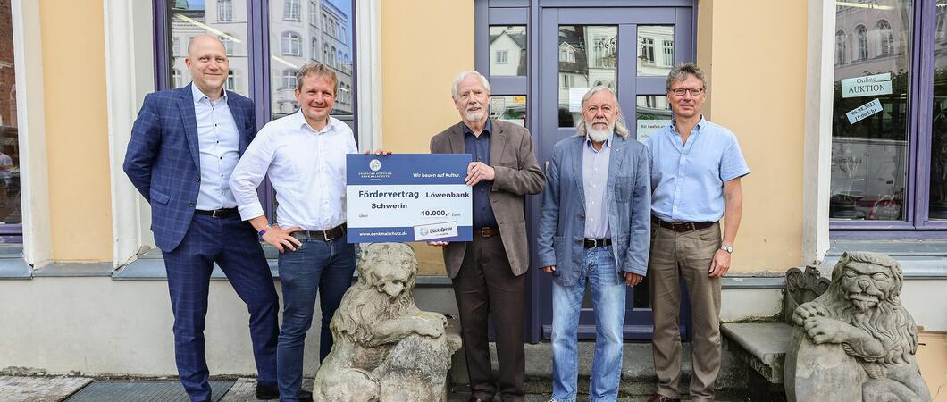 Wulf Kawan (M.), Ortskurator der Deutschen Stiftung Denkmalschutz, und Oberbürgermeister Rico Badenschier (2.v. l.) mit dem Förderbescheid zur Erhaltung der historischen Löwenbank vor der ehemaligen fürstlichen Apotheke, Foto: maxpress