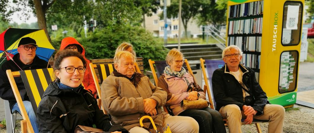 An der Tauschbox der WGS am Berliner Platz rückten die Zuhörer bei Regen zusammen und lauschten interessiert der Lesung von Schauspieler Martin Neuhaus aus „Bonnie Propeller”