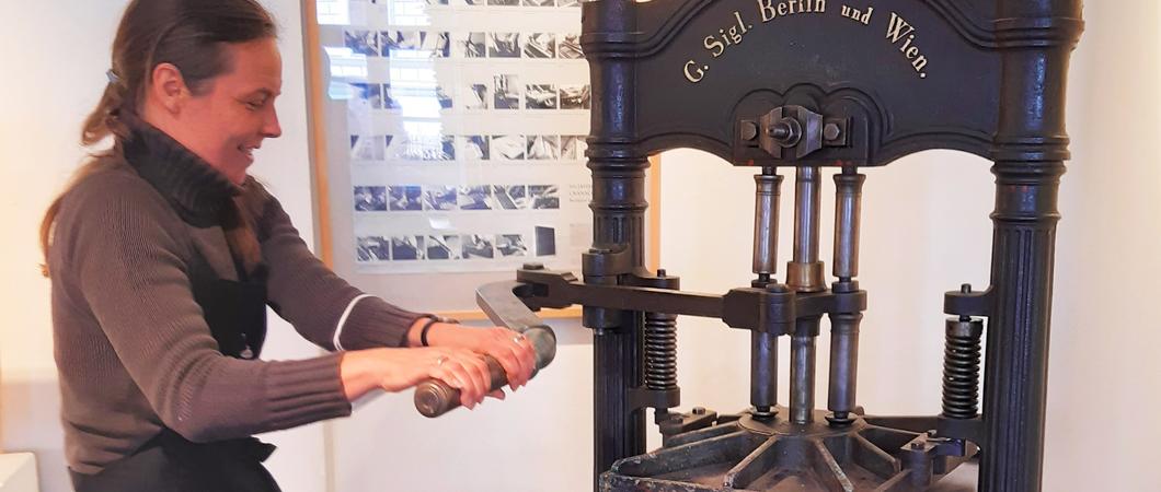 Sorgfalt und jede Menge Körpereinsatz sind nötig, um die 170 Jahre alte Druckerpresse in Bewegung zu bringen. Das kann Birgit Schattinger aus eigener Erfahrung bestätigen.