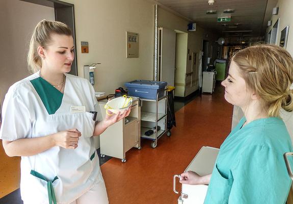 V.l.: Vanessa Otto zeigt der Gesundheits- und Krankenpflegerin Sarah Werner, wie sie eine FFP 2 Schutzmaske richtig einsetzt, Foto: Helios/mu